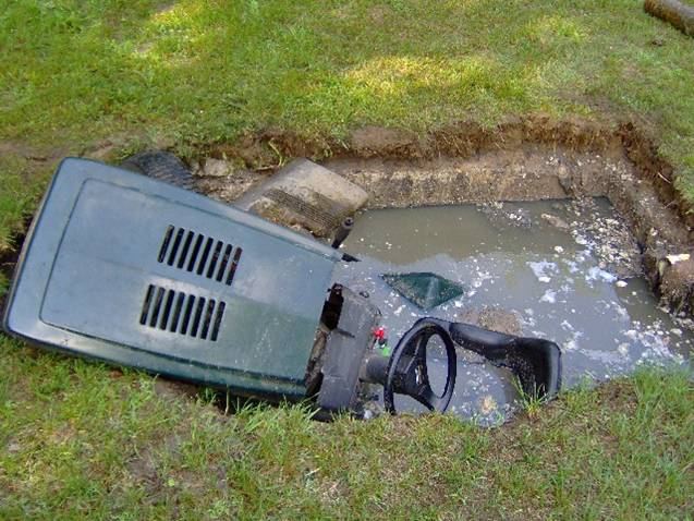 Lawn mower fallen into flooded collapsed septic tank opening